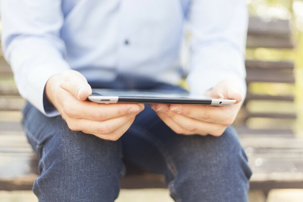 Mężczyzna z tabletem na ławce w parku