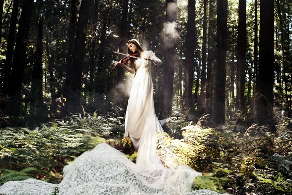 A girl with a violin in a beautiful forest
