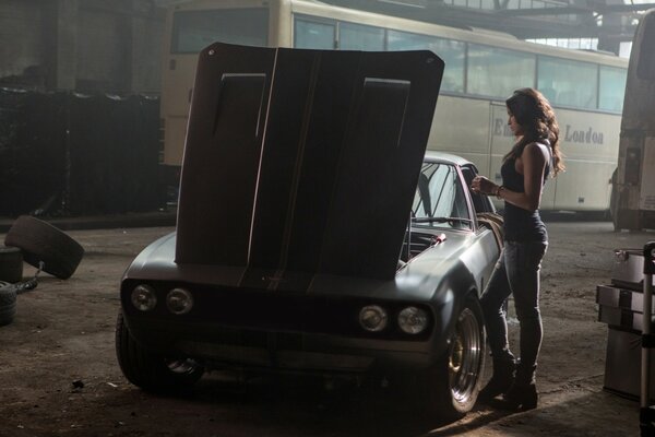 A beautiful girl repairs a car