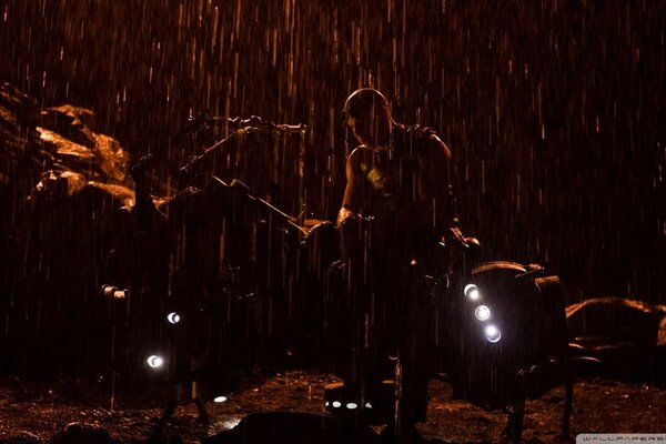 Silhouette of a man standing in the rain next to the floodlights