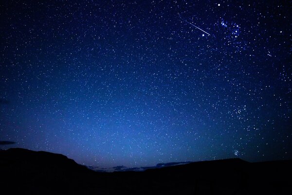 Starry sky and meteors on the background of mountains