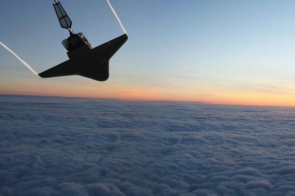 The shuttle behind the clouds above the surface of the earth