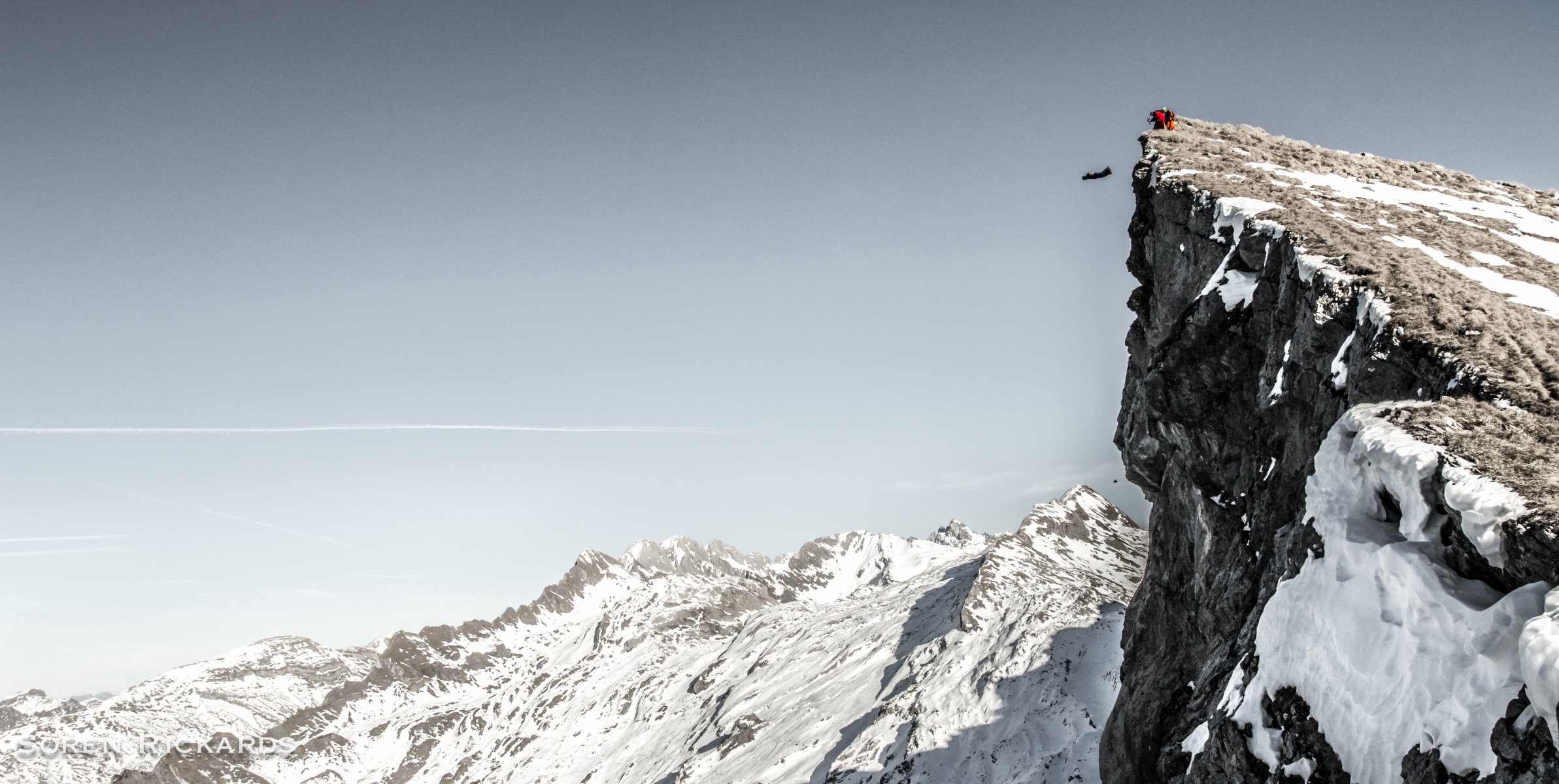 traje de alas piloto salto base base montañas rocas nieve invierno cielo sendero de humo contenedor paracaídas deportes extremos