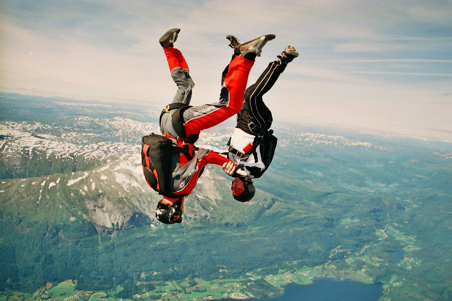 parachutists parachuting freeflying headdown mountain valley sky clouds trailers parachute