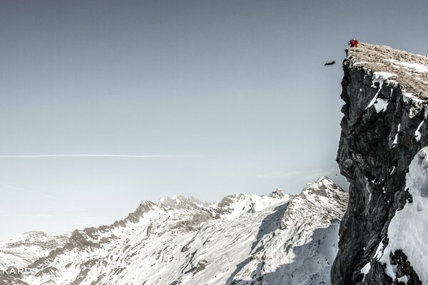 Base jumping from a snow-covered cliff in the mountains