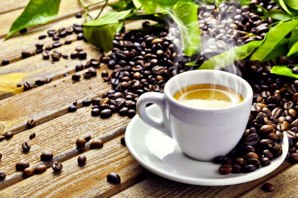 Tazza con caffè caldo e chicchi sul tavolo