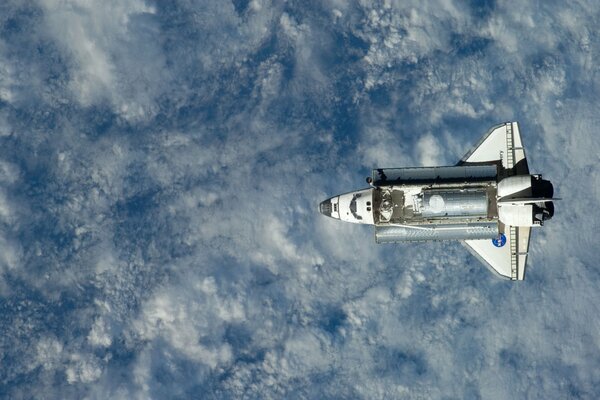 Ein Shuttle im Weltraum über Erde und Wolken