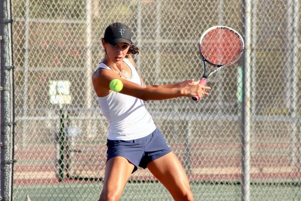 A girl with a racket hits a tennis ball