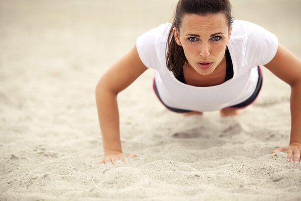 A woman does push-ups on the sand