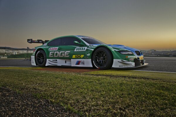 Sports car in the field on the background of sunset