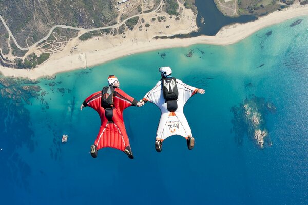 Two people are engaged in extreme sports over the sea