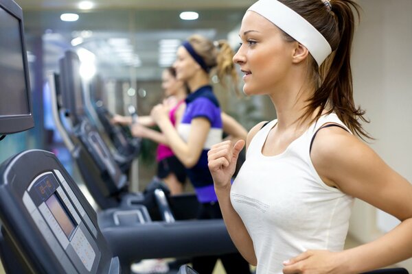 Fille sur le tapis roulant dans la salle de sport