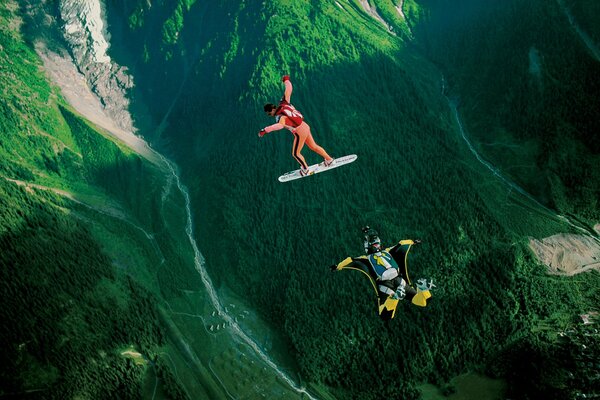 Parachutists are engaged in sky surfing over a mountain valley