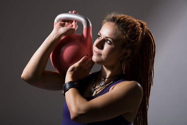 Rothaarige Mädchen mit Dreadlocks und Kettlebells