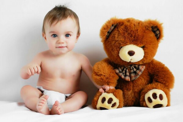 A baby in a diaper next to a bear