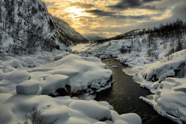 Ein Fluss ohne Eis in einer Winterlandschaft
