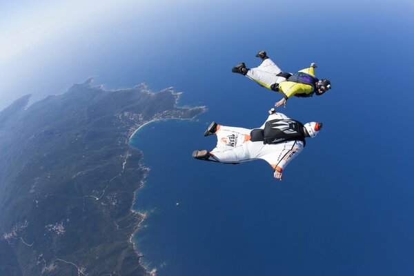 Two wingsuits soar over the sea