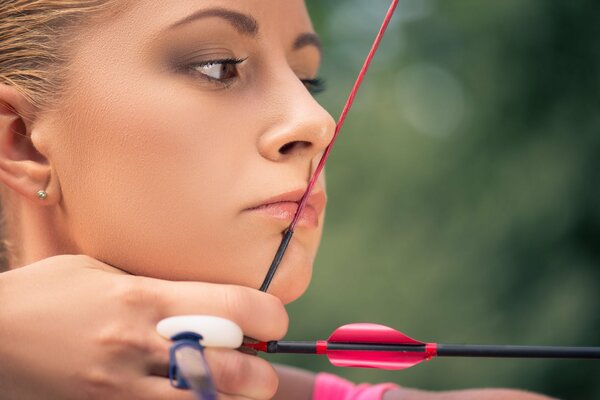 The girl pulled the bowstring when shooting from the bow