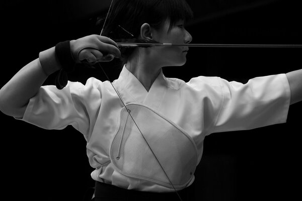 Japanese girl in white clothes shoots an arrow