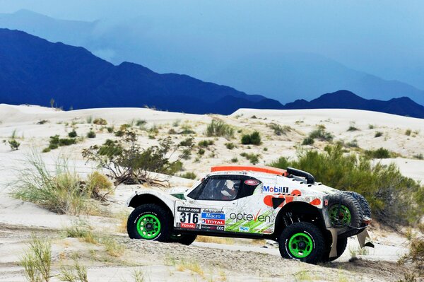 Weißer Buggy im Sand der Rallye 2014 Dakar mit grünen Rädern