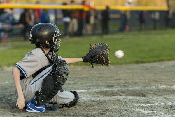 Der junge Baseballspieler sitzt auf dem Feld