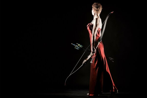 Arquera con un vestido rojo sobre un fondo oscuro