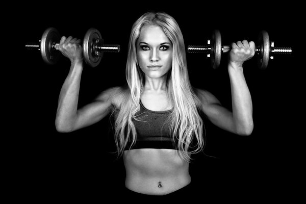 A girl with loose long hair lifted dumbbells