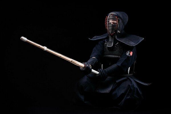 Un combattant de kendo en uniforme noir prêt à affronter un adversaire