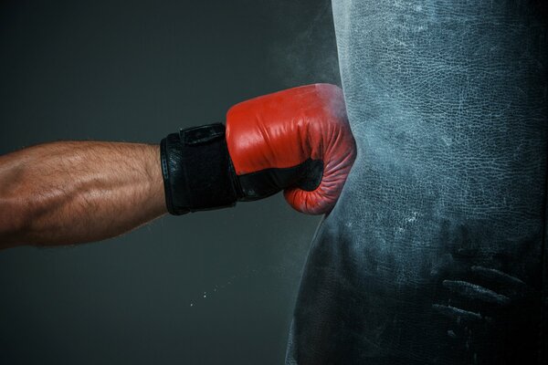 The blow of a fighter in a red glove on a pear