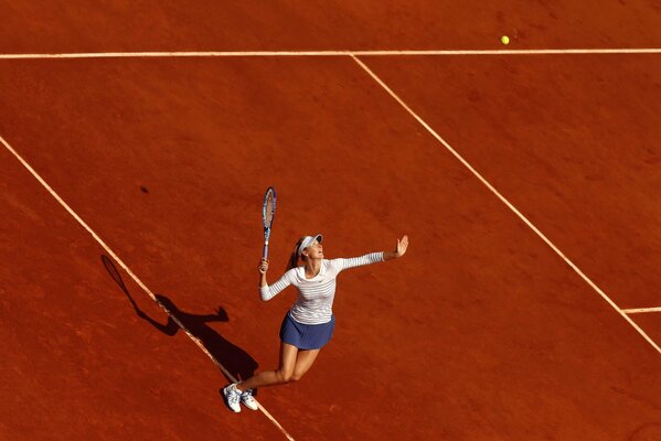 Sharapova with a tennis racket throws the ball under the sun