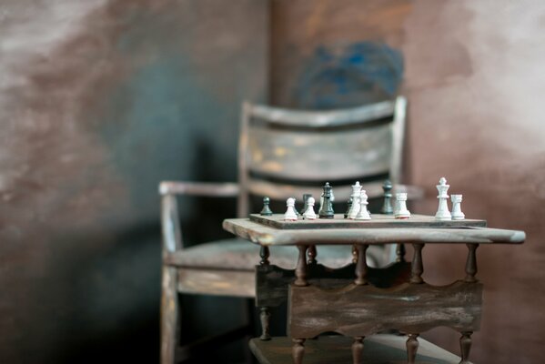 A chair with a table and a chess board with pieces