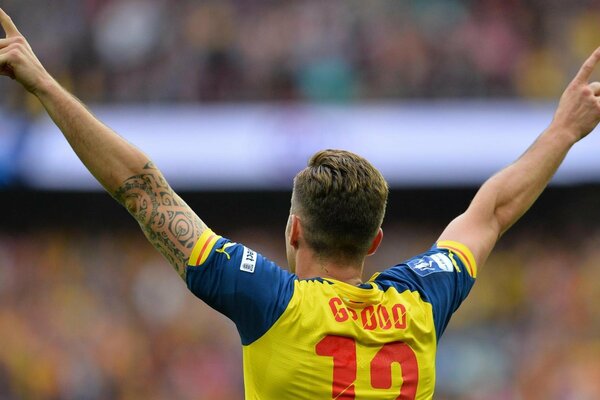 A football player with his hands raised looks at the stands