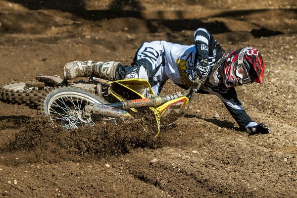 A motorcyclist in a red helmet who fell on the sand