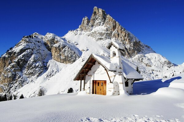 On the mountain there is a house in snowdrifts. Winter in the mountains