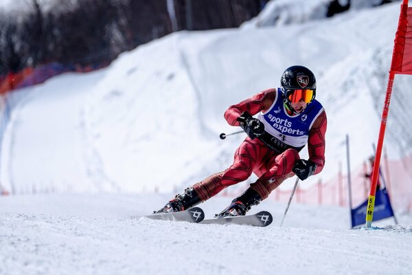 A skier in a red suit rushes along a snow track