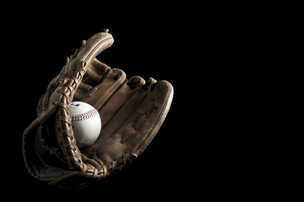 A ball in a baseball glove on a black background