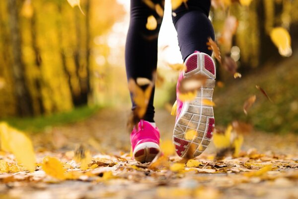 Un hombre corre por un camino de otoño en Zapatillas de deporte