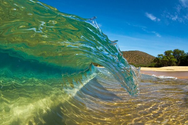Cresta de la ola con playa de arena