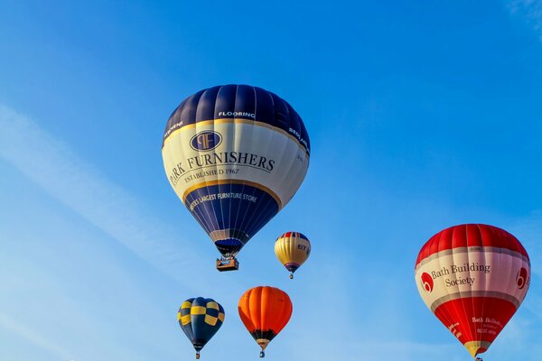 Five colored balloons fly across the blue sky