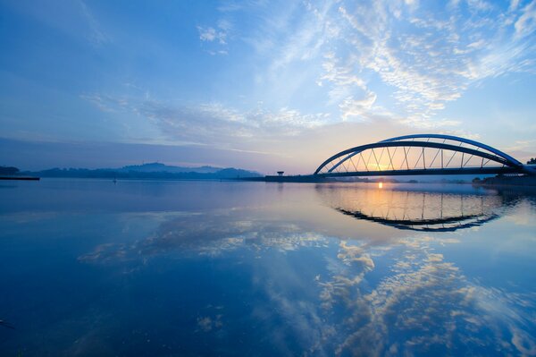 Most nad szeroką rzeką o zachodzie słońca