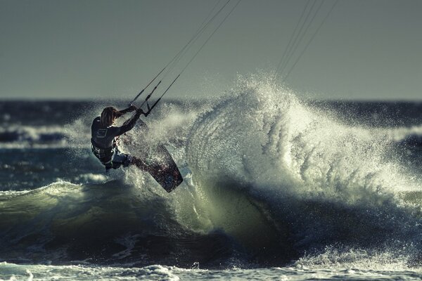 Kitesurfing athlete on the wave of the sea