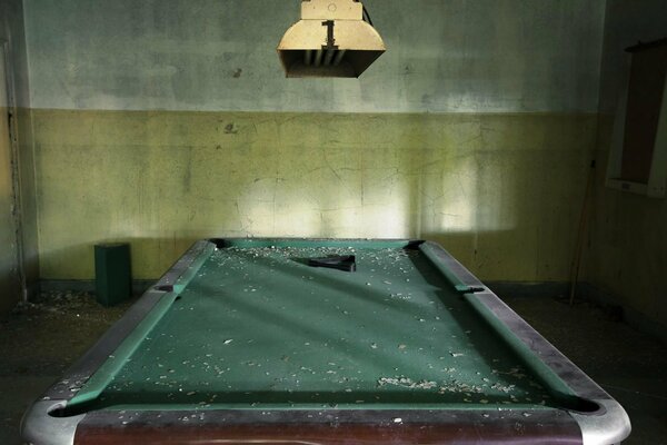 An abandoned room with dust on the billiard table