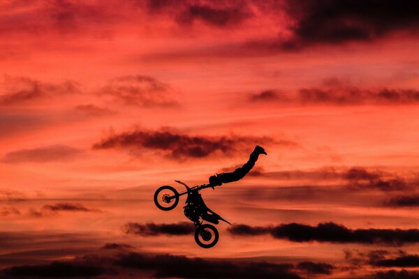 Stunt sur fond de nuages rouges sur une moto