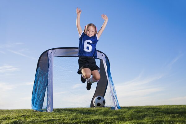 Girls with a ball on the football field. Blue sky