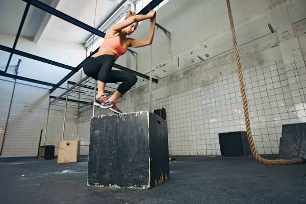 A girl is doing fitness on a gray cube