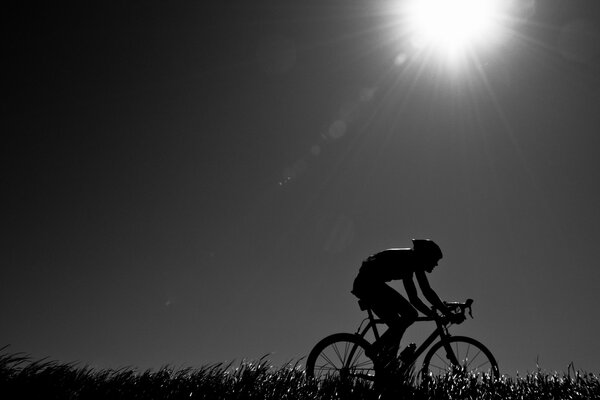 Ciclista sotto il sole della sera. Foto in bianco e nero del ciclista