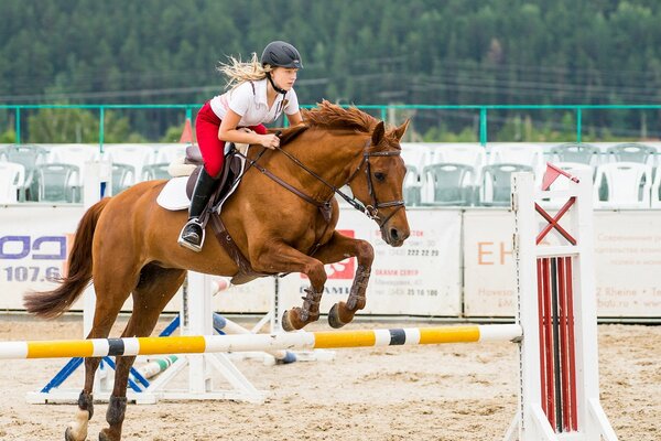 Atleta ragazza a cavallo attraverso gli ostacoli