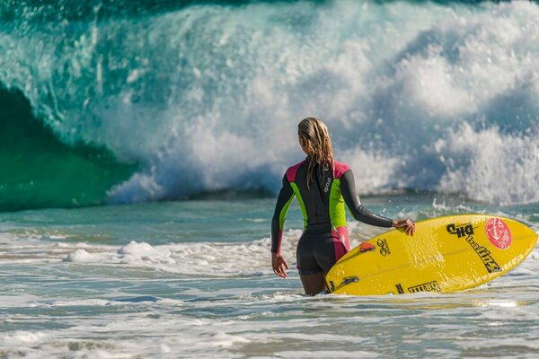 Mädchen mit Surfbrett auf dem Hintergrund der Welle