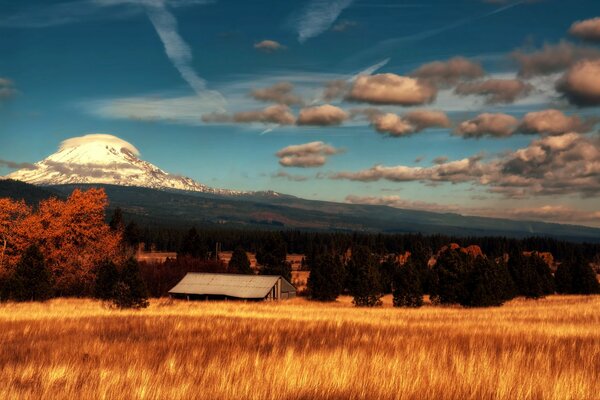 Hay una casa en el campo. Las nubes flotan en el cielo escondiéndose detrás del horizonte y cONGELÁNDOSE junto a la montaña