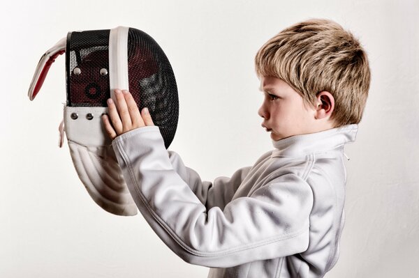 Young swordsman s costume boy looks at helmet